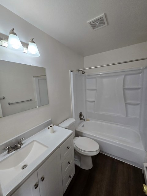 A white bathroom with a toilet, sink, and bathtub.