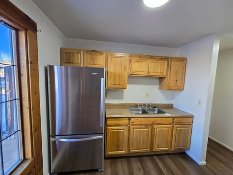 A kitchen with a stainless steel refrigerator and wooden cabinets.
