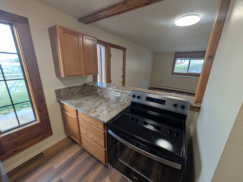A kitchen with a black stove top oven and wooden cabinets.