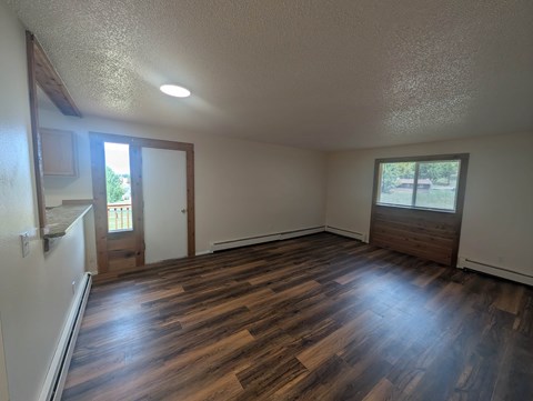 A room with wooden floors and a window with a view of trees.