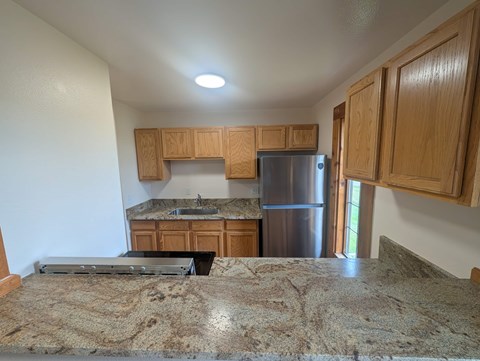 A kitchen with wooden cabinets and a granite countertop.