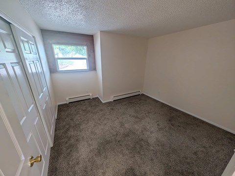 A room with a carpeted floor and a window.