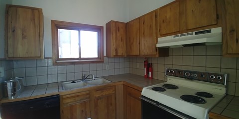 A kitchen with wooden cabinets and a white stove top oven.
