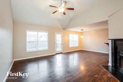 A spacious room with wood flooring and a ceiling fan.