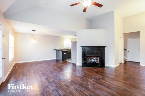 A spacious living room with a fireplace and wooden floors.