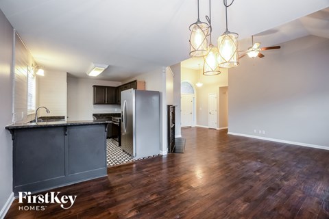 A kitchen area with wooden floors and a refrigerator.