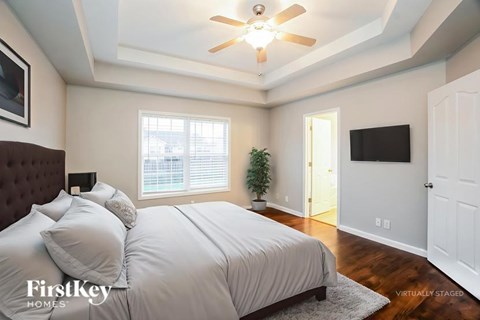 A bedroom with a bed, a ceiling fan, and a television.