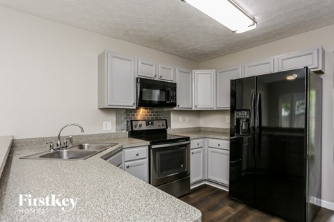 A kitchen with a black refrigerator and white cabinets.
