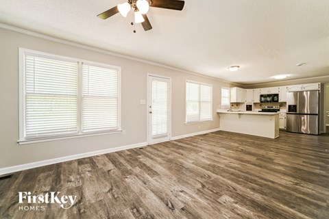A spacious kitchen and living room with wood flooring and a ceiling fan.