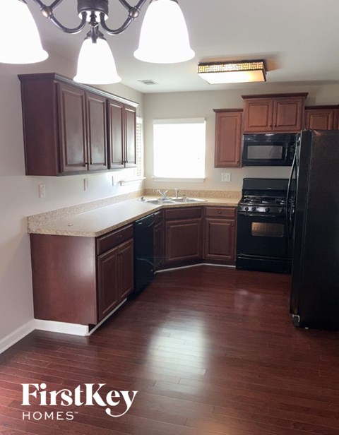 A kitchen with wooden cabinets and a black refrigerator.