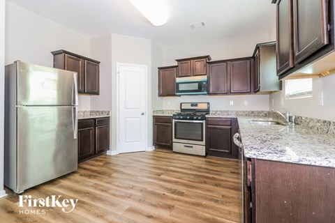A kitchen with wooden floors and a stainless steel refrigerator.