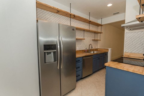 A modern kitchen with a stainless steel refrigerator and wooden shelves.