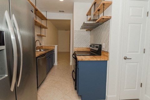 A kitchen with a stainless steel refrigerator and blue cabinets.