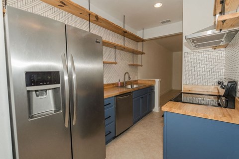 A modern kitchen with a stainless steel refrigerator and blue cabinets.