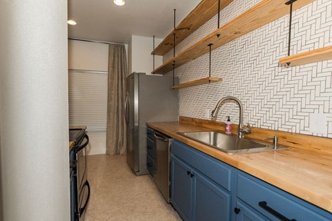 A kitchen with blue cabinets and a wooden countertop.