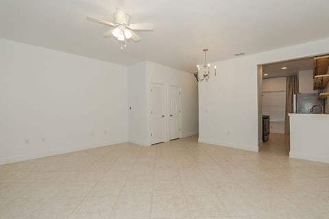 A spacious room with a ceiling fan and a chandelier.