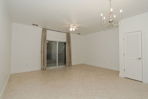 A room with a chandelier, sliding glass doors, and a white door.