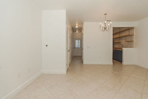 A large empty room with a chandelier and a doorway leading to another room.