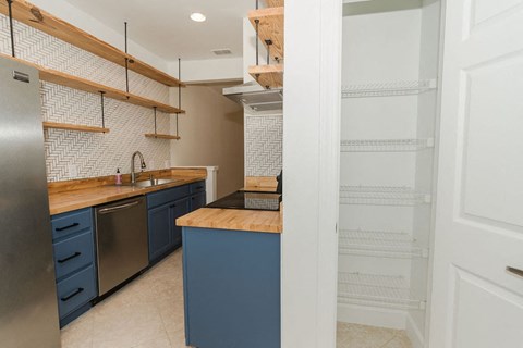A kitchen with a blue island and white cabinets.