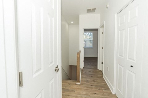A hallway with white doors and a wooden floor.