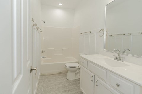 A white bathroom with a toilet, sink, and shower.