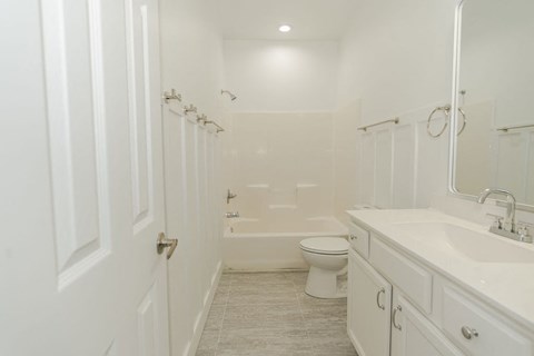 A white bathroom with a toilet, sink, and shower.