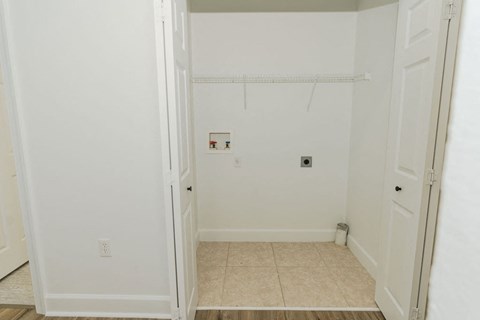 A white closet with a door open to a bathroom.