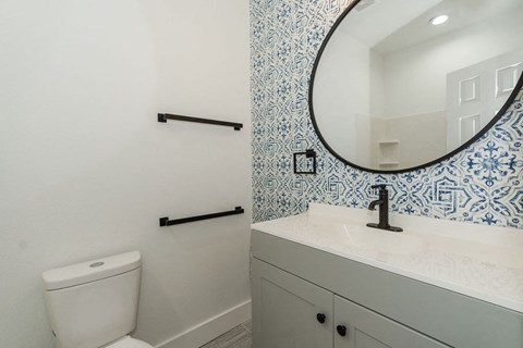 A bathroom with a toilet, sink and mirror.