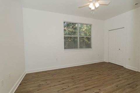A room with a ceiling fan and a window with blinds.