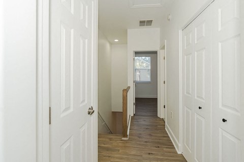 A hallway with white doors and a wooden floor.