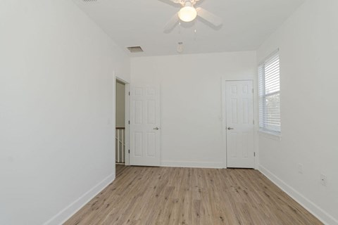 A room with a ceiling fan and wooden flooring.