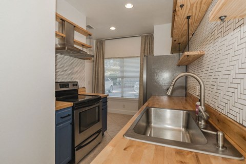 A modern kitchen with a stainless steel sink and a wooden countertop.