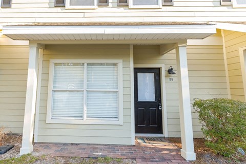 A house with a black door and window is numbered 56.