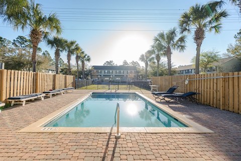 A pool surrounded by palm trees and wooden fences.