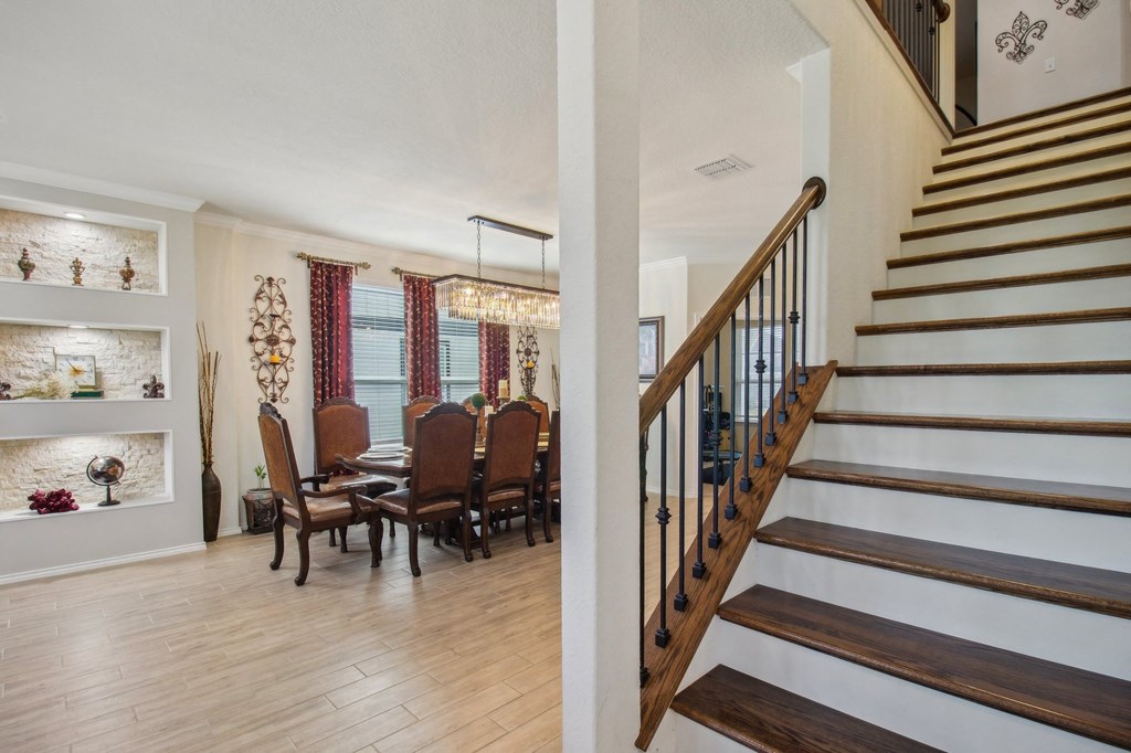 A staircase with a wooden banister and a dining room with a table and chairs.