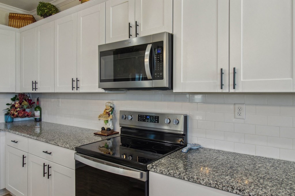 A kitchen with a granite countertop and white cabinets.