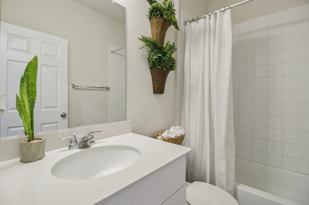 A white bathroom with a white sink and a white toilet.