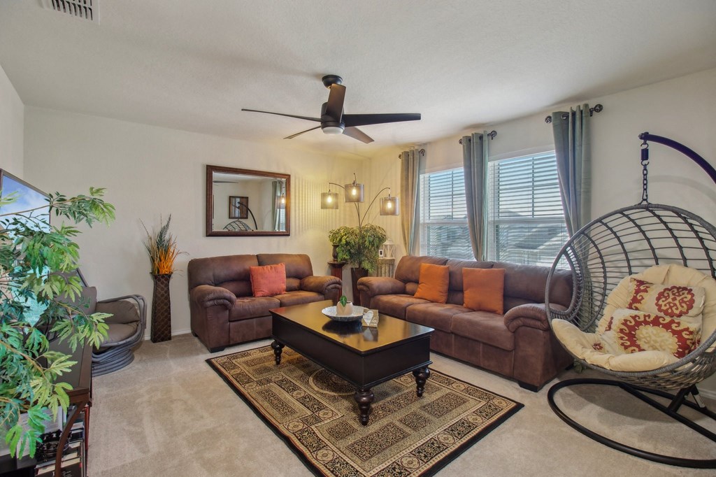 A living room with a brown couch, a coffee table, and a ceiling fan.