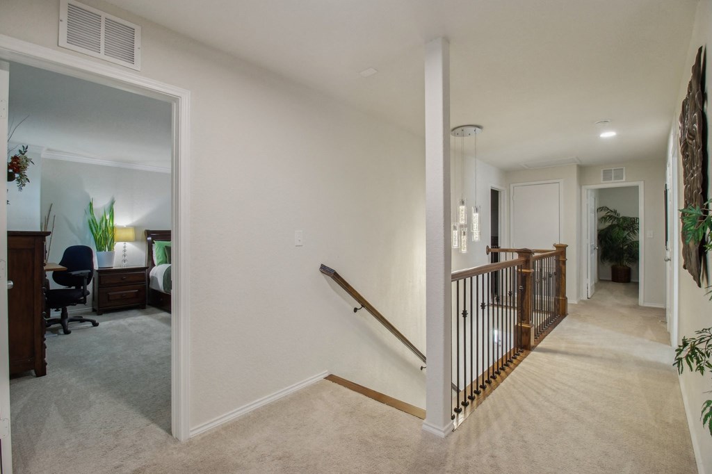 A hallway with a staircase and a chair.