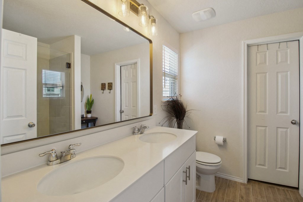 A white bathroom with a sink, mirror, and toilet.