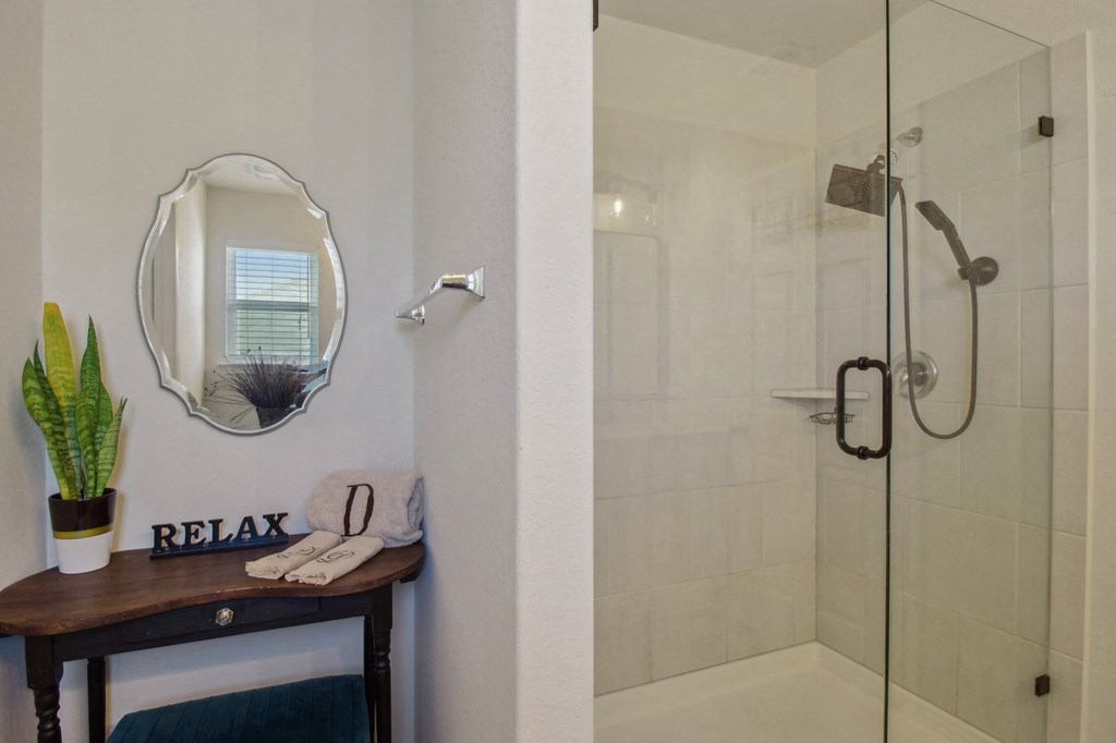 A bathroom with a mirror, a plant, and a towel on a table.