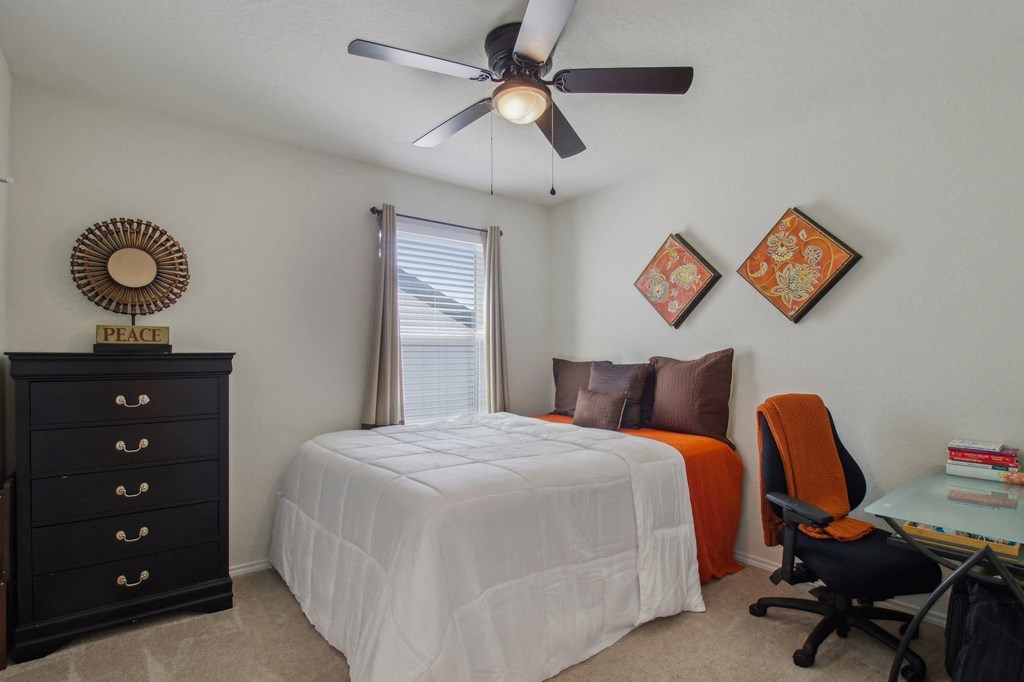 A bedroom with a bed, chair, and dresser.