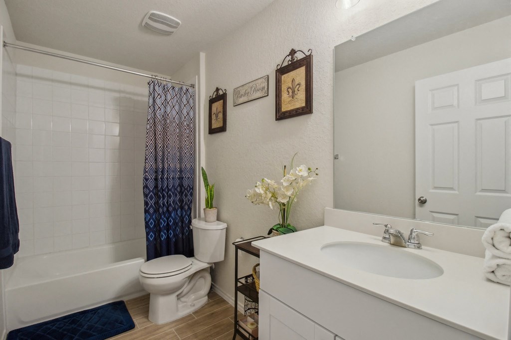 A white bathroom with a toilet, sink, and shower.