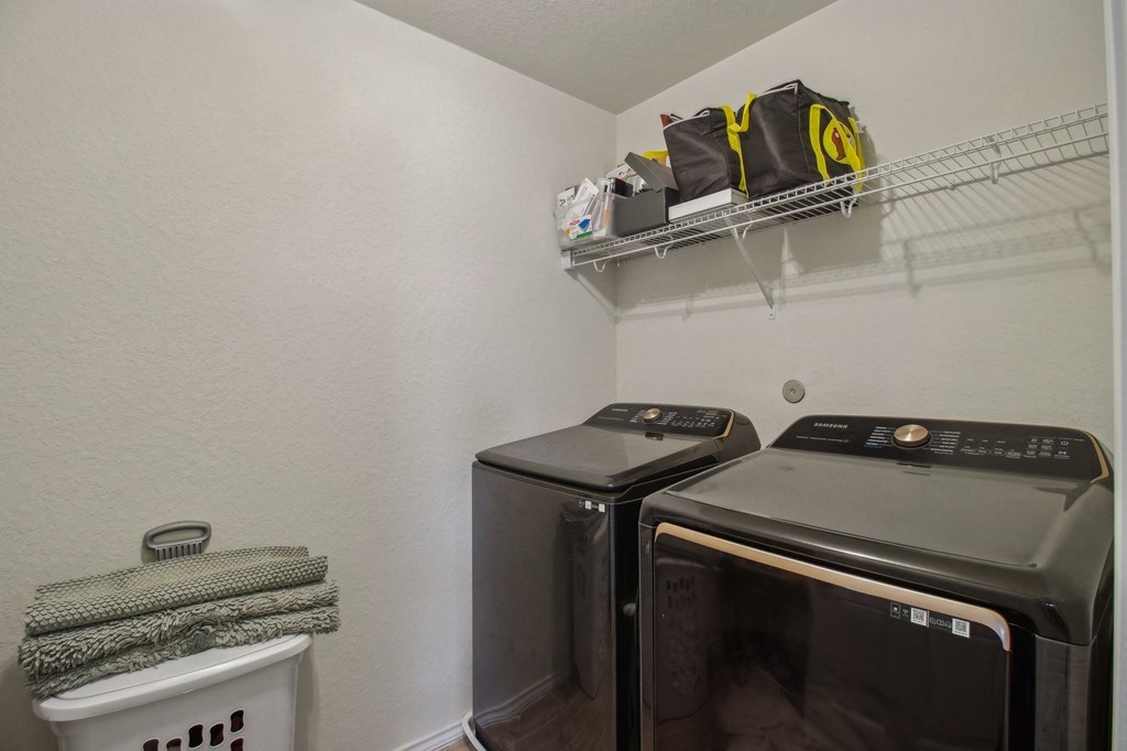 A small kitchen with a white wall and a shelf with bags on it.