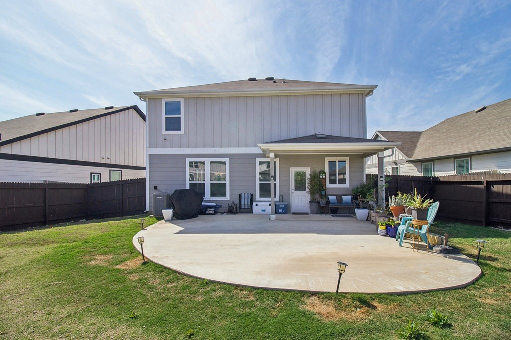A house with a grey and white exterior has a patio with a table and chairs.