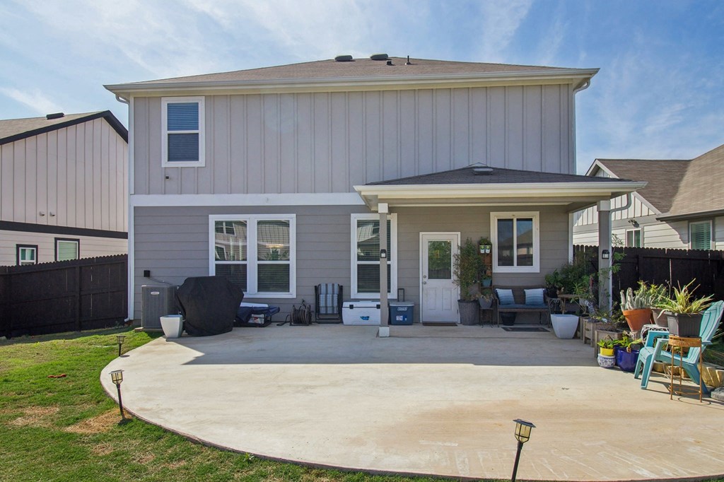 A house with a grey exterior and a patio with chairs.