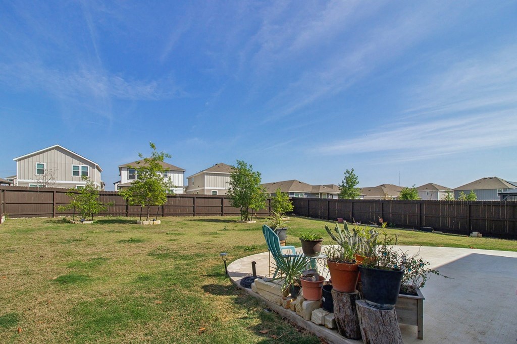 A backyard with a fence, a bench, and potted plants.