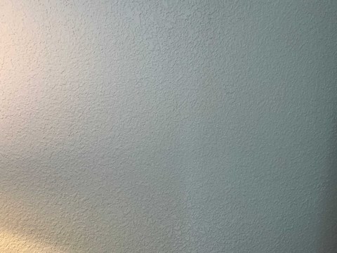 A wall with a textured surface and a light source on the left.