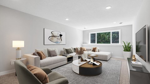 A modern living room with a grey couch, a coffee table, and a painting on the wall.