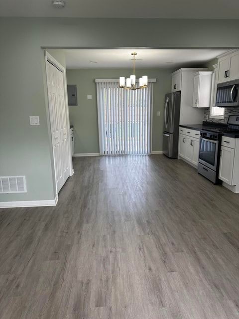 A kitchen with white cabinets and a grey floor.